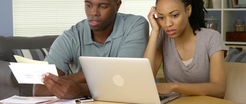 Frustrated young Black couple going over bills and finances online