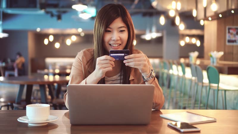 Asian businesswoman in casual suit using the credit card with computer for online shopping at co-working space, business technology and lifestyle concept