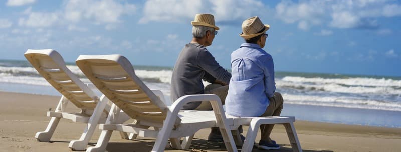 Senior couple sitting on chairs on the beach and looking at the ocean in a romantic,Elderly life insurance,Men take care of each other when aging.